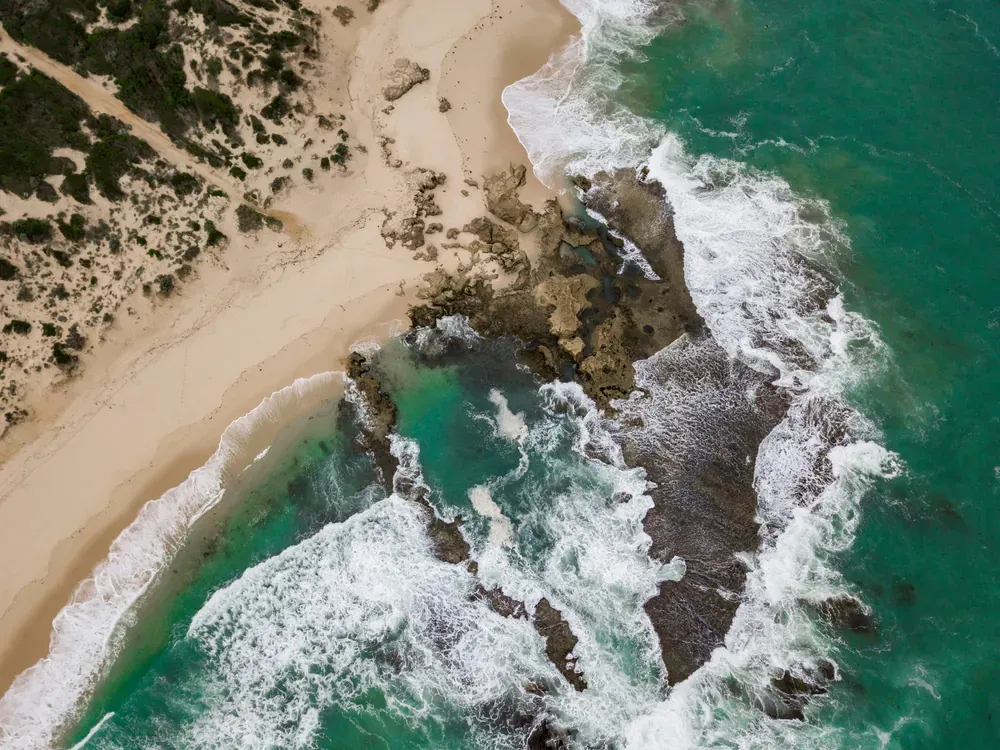Aerial view of a surf beach, sand dunes and rock reef on the Bass Strait coast of the Mornington Peninsula