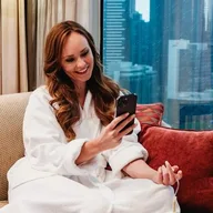 A woman in a robe booking a SOUL IV infusion on her phone at home