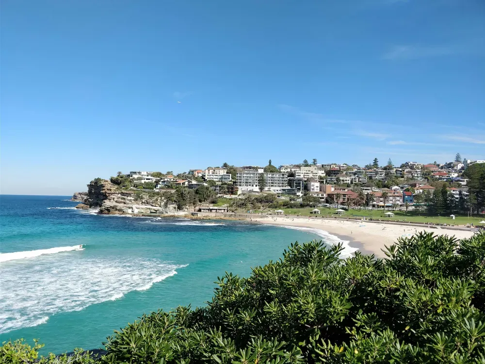 The coastline of Sydney’s Eastern Suburbs from the clifftop coastal walk, with surf breaking below a headland of houses