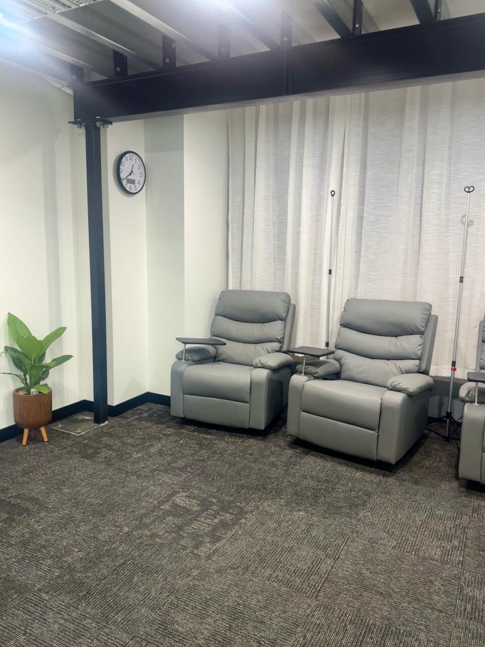 SOUL IV treatment room with two grey recliner chairs, IV stands and natural light through sheer curtains