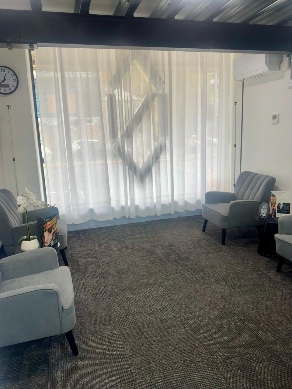 SOUL IV clinic waiting area with grey velvet armchairs and sheer curtains, SOUL IV diamond logo visible on window